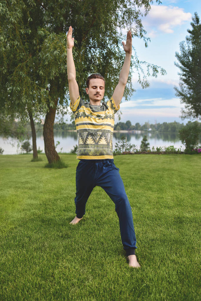 Man performing yoga young fitness man outdoor doing exercise. leg stretch - Fotó, kép