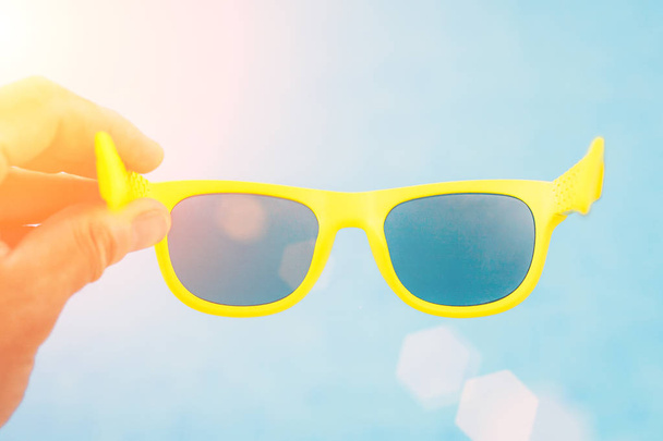 Sunglasses in hand against sky background - Фото, зображення