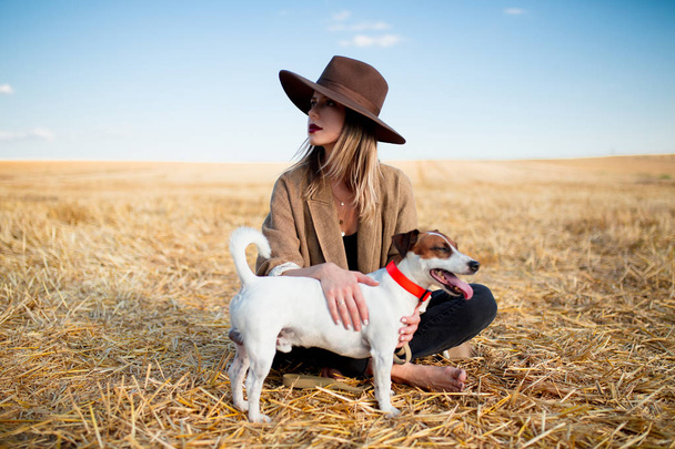 Woman in hat with dog on field - Фото, изображение