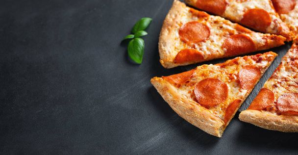 Smakelijke pepperoni pizza op zwarte betonnen achtergrond. Top uitzicht op hete pepperoni pizza. Met Kopieer ruimte voor tekst. Platte lag. Banner - Foto, afbeelding