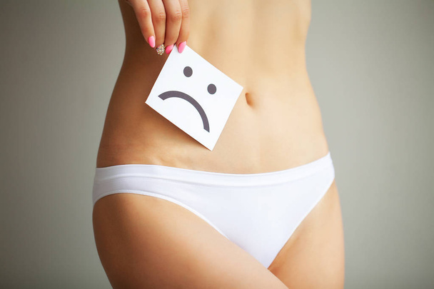 Woman Health Problem. Closeup Of Female With Fit Slim Body In Panties Holding White Card With Sad Smiley Face Near Her Stomach. Digestive Disorders, Period Pain, Health Issues Concept - Photo, Image