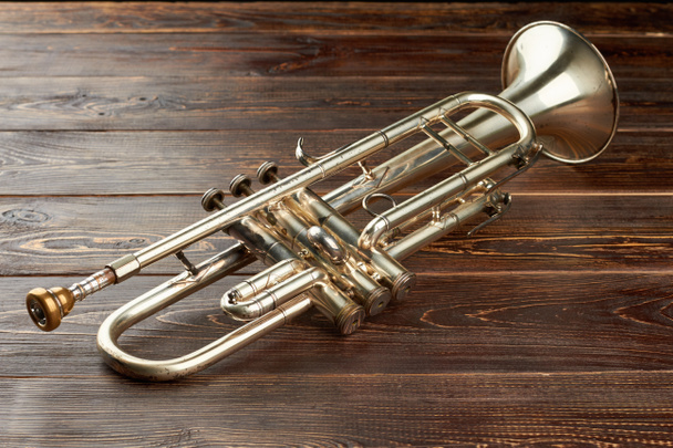 glänzende Trompete auf braunem Holzgrund. - Foto, Bild