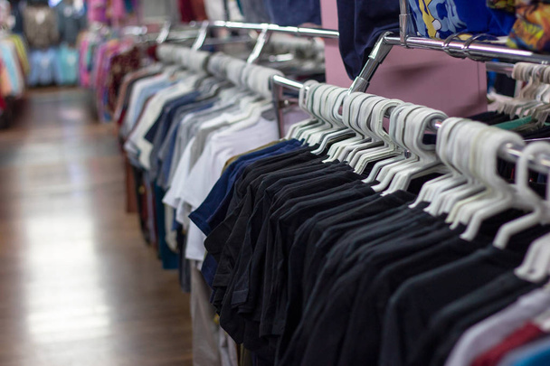 Many different colorful clothes on a hanging rack in the retail shop store. Soft selective focus photography - Photo, Image