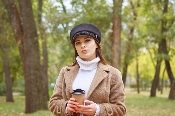 Beautiful woman in autumn park with coffee - Valokuva, kuva