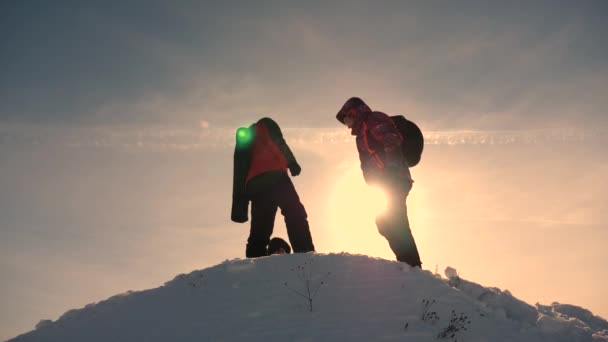 Три туриста с рюкзаками зимой встретились на холме в лучах солнца. Альпинисты на вершине снежной горы. Командные путешественники. спортивный образ жизни
 - Кадры, видео