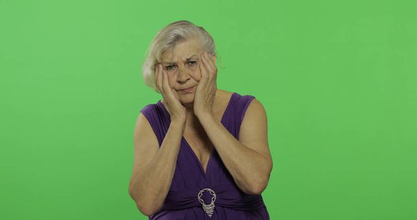 Una anciana sufre de dolor de cabeza problemas de dolor. Vieja abuela. Clave de croma
 - Foto, imagen