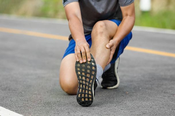 Male middle aged having a cramp while jogging. Stop and massage calf - Photo, Image