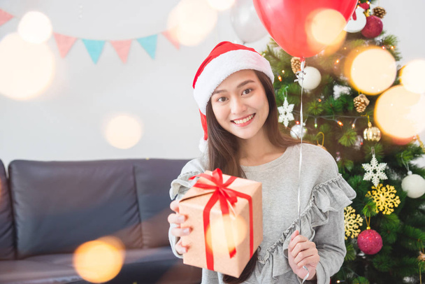 schöne asiatische Mädchen trägt Weihnachtsmann Hut und hält Geschenkbox - Foto, Bild