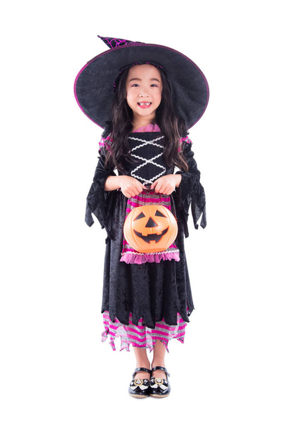 Πλήρες μήκος του μικρού κοριτσιού φορώντας αποκριάτικες στολές και κρατώντας καλάθι κολοκύθας  - Φωτογραφία, εικόνα
