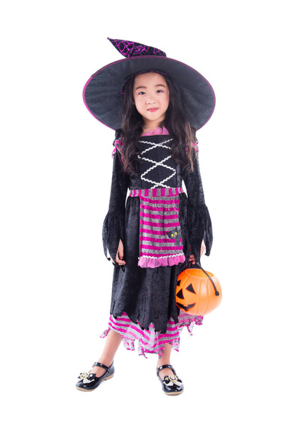 Full length of little girl wearing halloween costume and holding pumpkin basket  - Zdjęcie, obraz