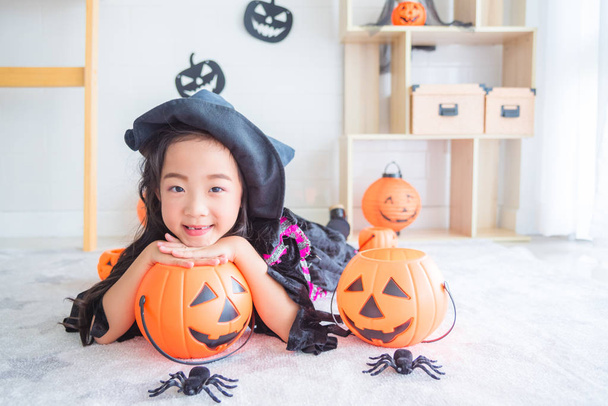 Little asian girl in witch costume lying on the floor in room  - Photo, image