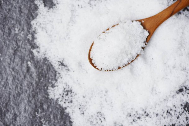 Salt in wooden spoon and heap of white salt on dark background t - Photo, Image