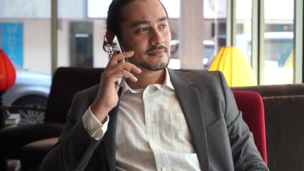 handsome asian businessman sitting at cafe with smartphone - Felvétel, videó