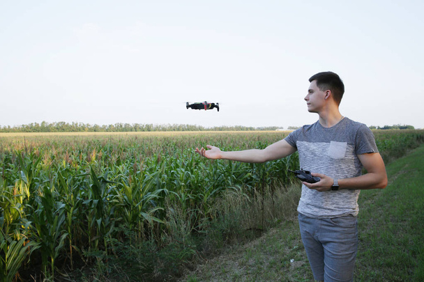 активный молодой человек использует квадроцикл, чтобы летать вокруг кукурузного поля. Он управляет беспилотником с дистанционным управлением. Концепция новых технологий и инноваций в сельском хозяйстве
. - Фото, изображение