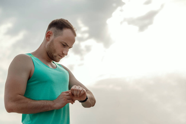 portrait of Caucasian guy in azure t-shirt looking at fitness tr - Valokuva, kuva