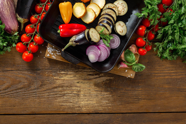 Varias verduras para cocinar en una parrilla sobre un fondo de madera vista superior espacio de copia
 - Foto, imagen