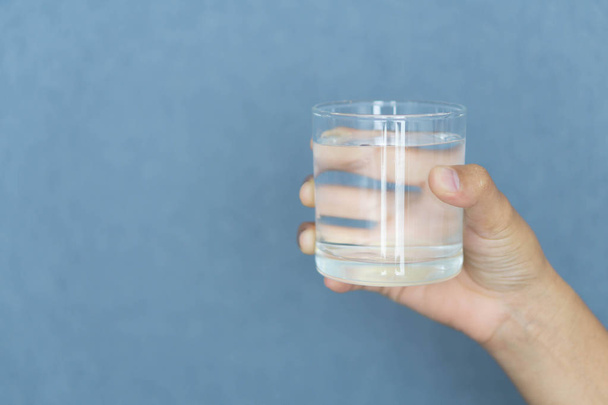 Close up woman hand holding a glass of pure water for dink with grey background, Health care concept - Φωτογραφία, εικόνα