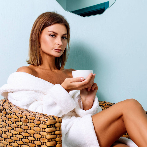Woman in bathrobe drinking tea in spa salon. - Fotoğraf, Görsel