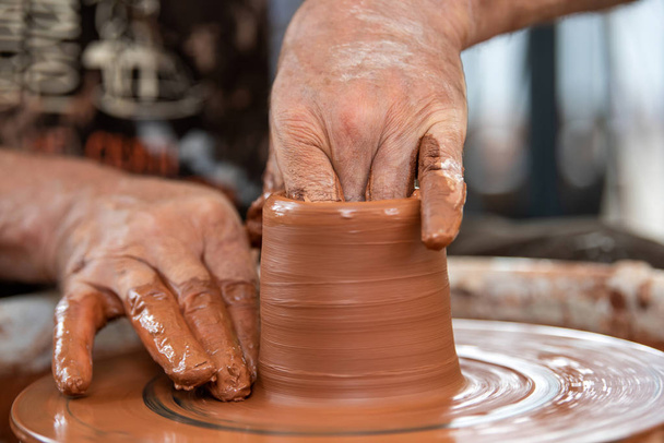 陶芸家は陶器の車輪に陶器の皿を作る - 写真・画像