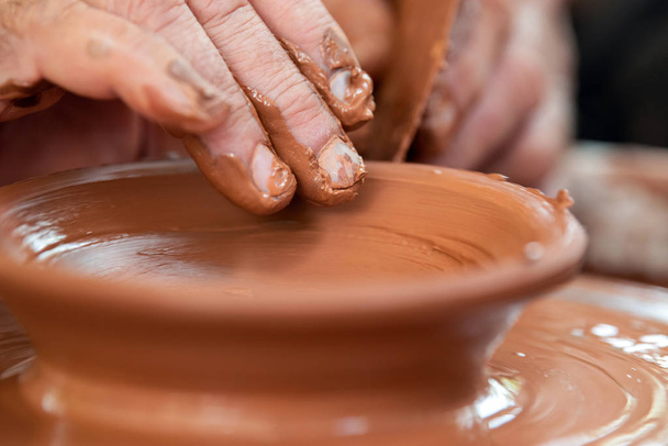 Potter makes pottery dishes on potter's wheel - Foto, Imagen