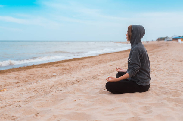 Woman practicing meditation on the seashore, ocean. Practice clearing thoughts, calming down. Yoga on the coast. - Photo, Image