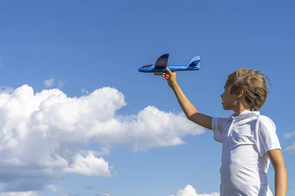 Kid playing with blue toy plane against blue sky - Zdjęcie, obraz