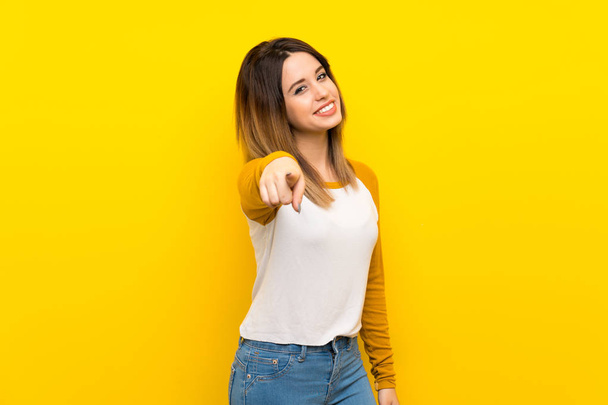 Jolie jeune femme sur un mur jaune isolé pointe du doigt vers vous avec une expression confiante
 - Photo, image