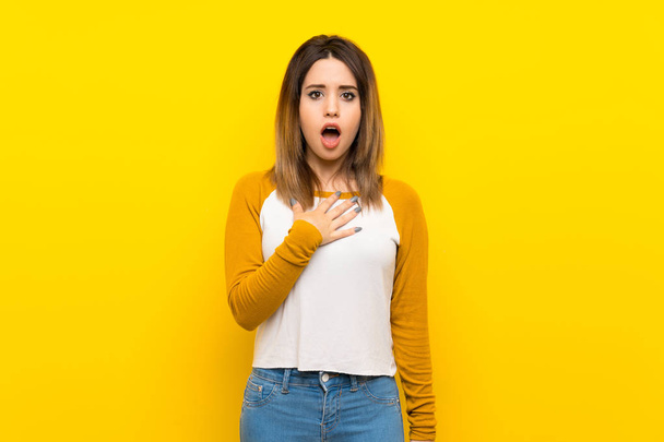 Pretty young woman over isolated yellow wall surprised and shocked while looking right - Photo, Image