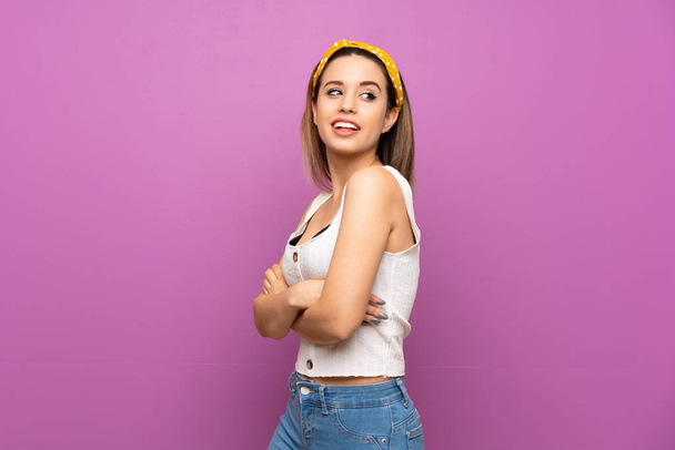 Красива молода жінка над ізольованою фіолетовою стіною з схрещеними і щасливими руками
 - Фото, зображення