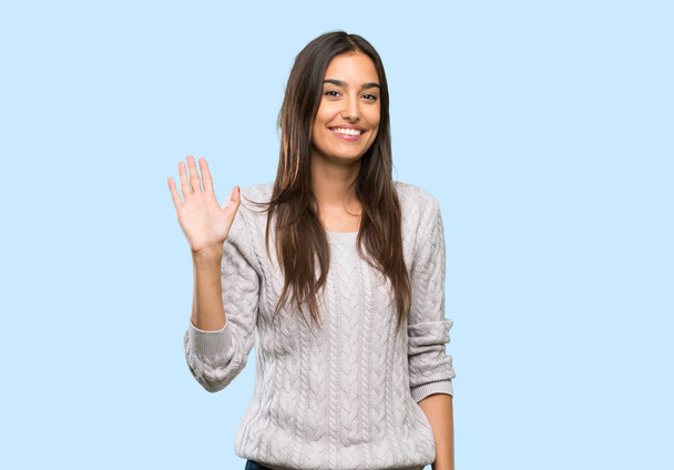 İzole arka plan üzerinde mutlu ifade ile el ile selamlayan genç İspanyol esmer kadın - Fotoğraf, Görsel