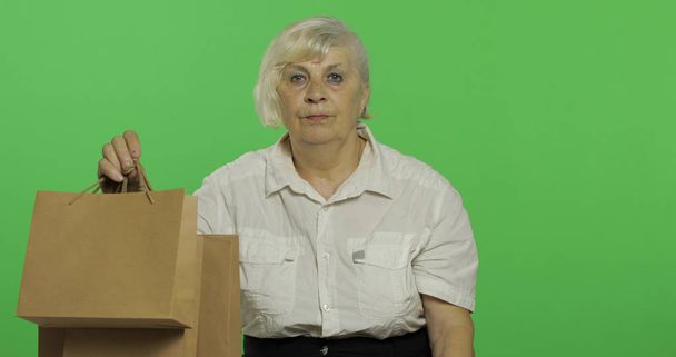 Alışveriş çantaları olan yaşlı bir kadın. Alışveriş. Sunar. Chroma anahtarı - Fotoğraf, Görsel