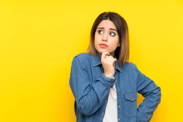 Young woman over yellow background having doubts with confuse face expression - Фото, изображение