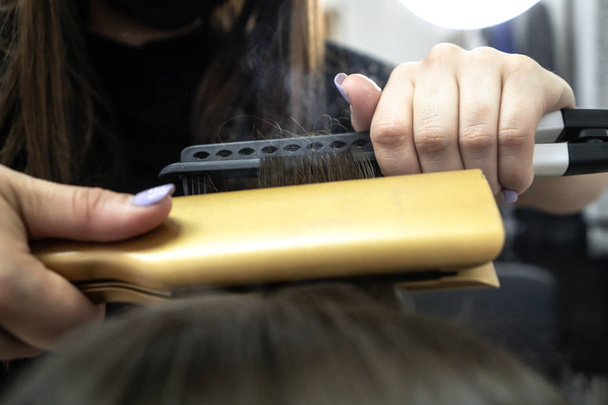 Χαριτωμένο κορίτσι με μακρά μελαχρινή Κομμωτήριο Κομμωτήρια κάνει πλαστικοποίηση μαλλιών σε ένα σαλόνι ομορφιάς. έννοια της περιποίησης μαλλιών, ατμός από τα μαλλιά - Φωτογραφία, εικόνα