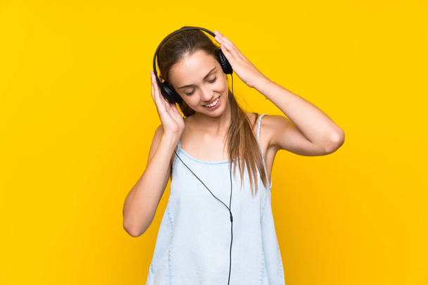 Jovem mulher ouvindo música sobre isolado amarelo parede cantando
 - Foto, Imagem
