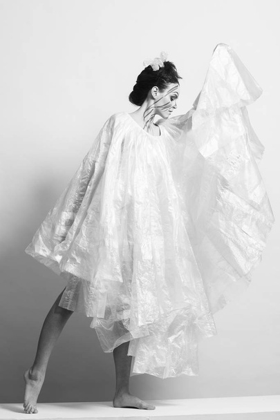 Model in a raincoat made of cellophane and in creative make-up - Zdjęcie, obraz