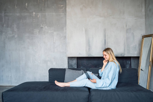 Image of happy woman using silver laptop while sitting on sofa - Photo, Image