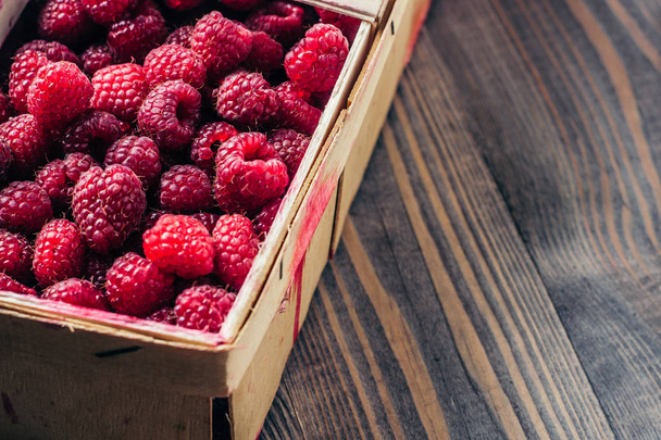 Fresh ripe juicy raspberries in a woven wooden box - Foto, Bild