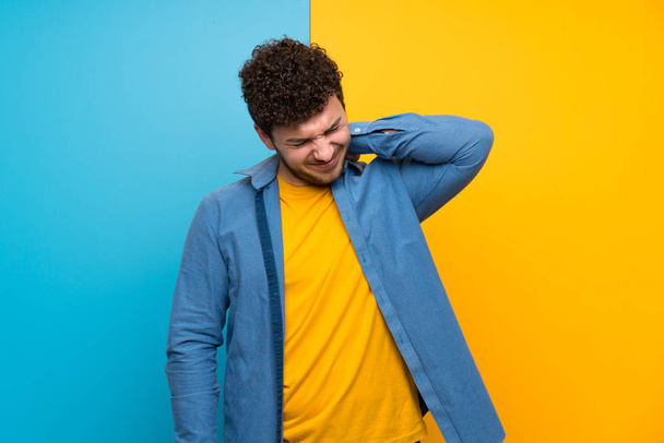 Man with curly hair over colorful wall with neckache - Фото, зображення