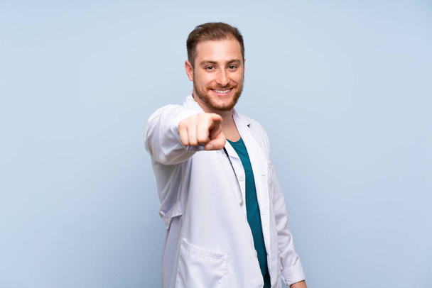 Bonito médico homem sobre azul parede aponta dedo para você com uma expressão confiante
 - Foto, Imagem
