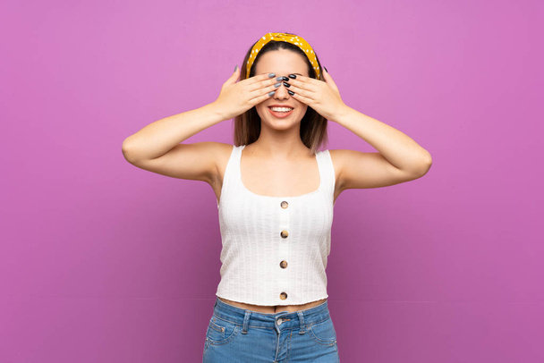 Красива молода жінка над ізольованою фіолетовою стіною, що закриває очі руками
 - Фото, зображення