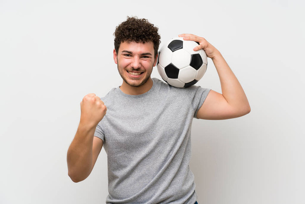 Człowiek z kręcone włosy na białym ścianie trzymając piłkę nożną - Zdjęcie, obraz
