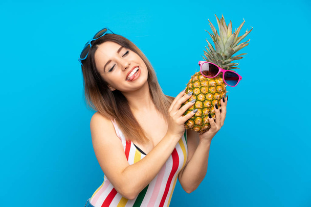 Fiatal nő a Nyári szünidő alatt kék háttér gazdaság egy ananász napszemüveg - Fotó, kép