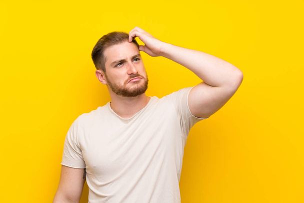 Handsome man over yellow background having doubts and with confuse face expression - Photo, Image