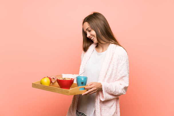 Jeune femme en robe de chambre sur le mur rose avec petit déjeuner
 - Photo, image