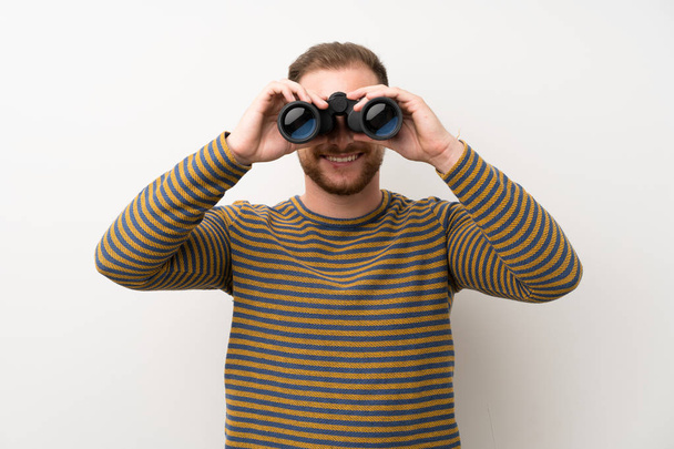 Handsome man over isolated white wall with black binoculars - Φωτογραφία, εικόνα