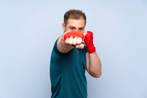 Blonde sport man over blue wall in boxing bandages - Photo, image