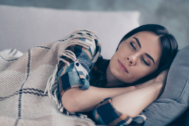 Close up side profile photo beautiful she her lady fell asleep hands arms under head eyes closed dreaming covered blanket wear checkered plaid shirt lying comfy divan flat house living room indoors - 写真・画像