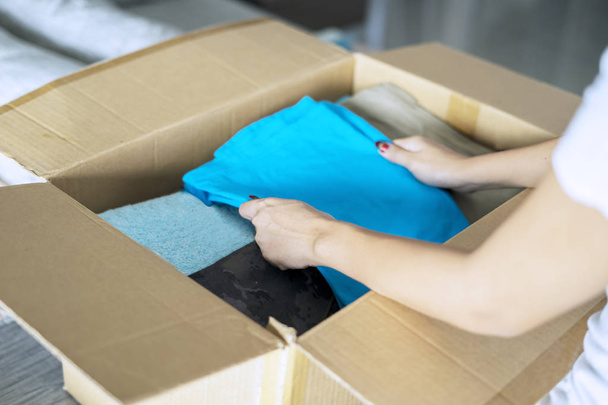 Woman putting old clothes in a cardboard box - Foto, Imagen