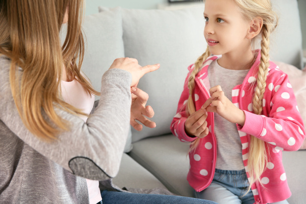 Mother teaching her deaf mute daughter to use sign language at home - Photo, Image