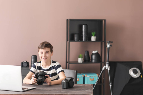 Mignon petit photographe assis à table dans un studio professionnel
 - Photo, image